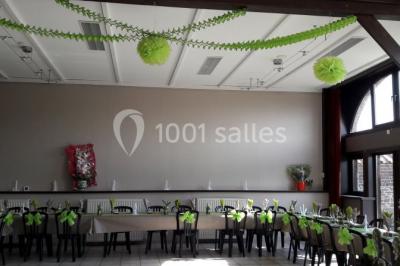 Jardin ensoleillé avec des palmiers au premier plan, pelouse verte et tables hautes recouvertes de nappes noires en arrière…