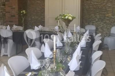 Jardin ensoleillé avec des palmiers au premier plan, pelouse verte et tables hautes recouvertes de nappes noires en arrière…