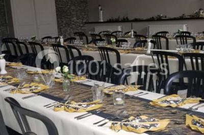 Jardin ensoleillé avec des palmiers au premier plan, pelouse verte et tables hautes recouvertes de nappes noires en arrière…