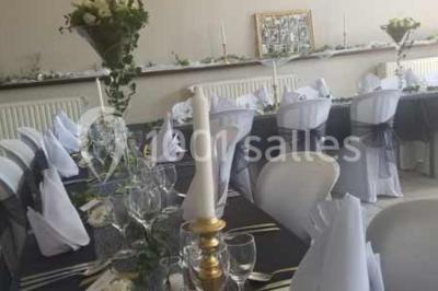 Jardin ensoleillé avec des palmiers au premier plan, pelouse verte et tables hautes recouvertes de nappes noires en arrière…