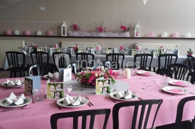 Jardin ensoleillé avec des palmiers au premier plan, pelouse verte et tables hautes recouvertes de nappes noires en arrière…