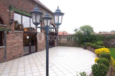 Jardin ensoleillé avec des palmiers au premier plan, pelouse verte et tables hautes recouvertes de nappes noires en arrière…