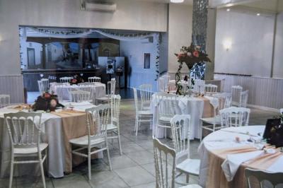 Terrasse en bois avec tables et chaises sous un parasol en chaume, entourée de végétation et de fleurs colorées.