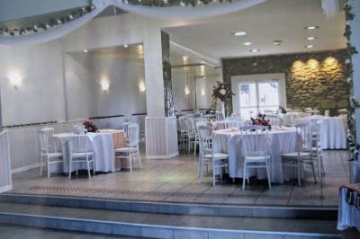 Terrasse en bois avec tables et chaises sous un parasol en chaume, entourée de végétation et de fleurs colorées.