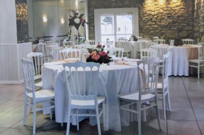 Terrasse en bois avec tables et chaises sous un parasol en chaume, entourée de végétation et de fleurs colorées.