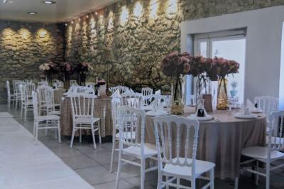Terrasse en bois avec tables et chaises sous un parasol en chaume, entourée de végétation et de fleurs colorées.