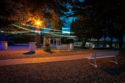 Terrasse en bois avec tables et chaises sous un parasol en chaume, entourée de végétation et de fleurs colorées.