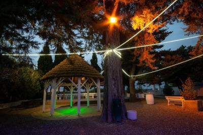 Terrasse en bois avec tables et chaises sous un parasol en chaume, entourée de végétation et de fleurs colorées.