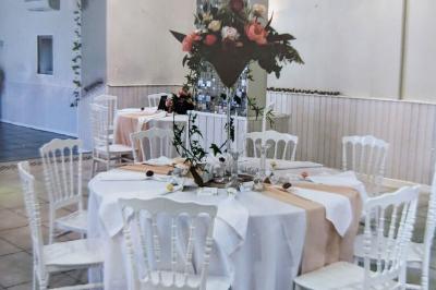 Terrasse en bois avec tables et chaises sous un parasol en chaume, entourée de végétation et de fleurs colorées.