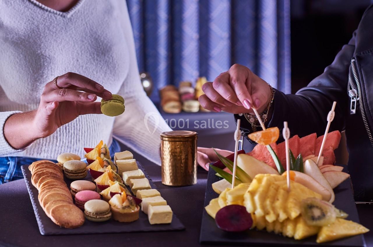 Deux personnes dégustent des desserts variés et des fruits frais présentés sur des plateaux élégants.