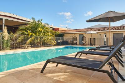 Salle de réunion avec tables rondes dressées de nappes blanches, chaises noires et fournitures de bureau.
