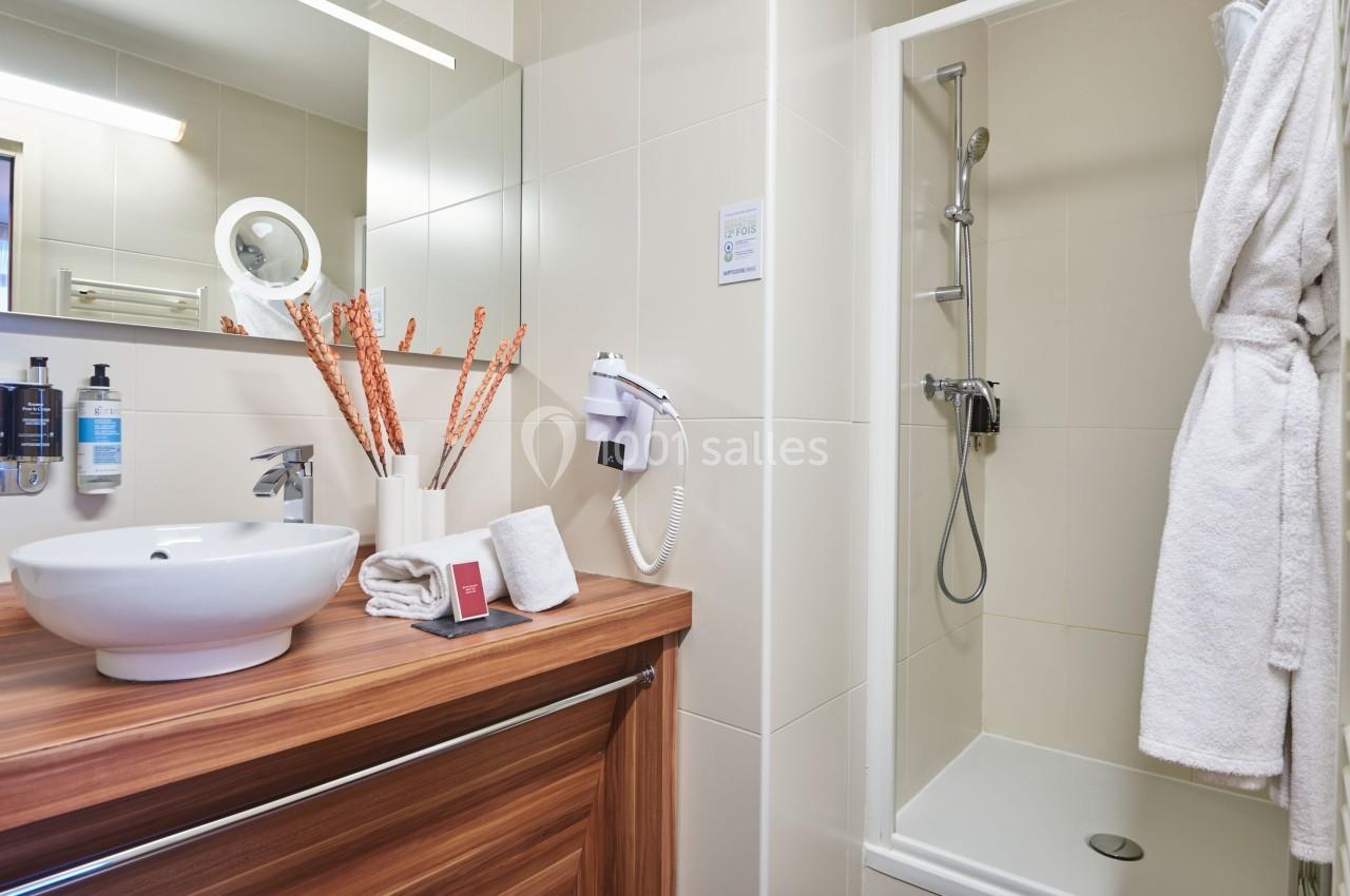 Salle de bain moderne avec lavabo sur meuble en bois, douche à l'italienne et accessoires de toilette.