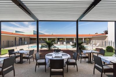 Salle de réunion avec tables rondes dressées de nappes blanches, chaises noires et fournitures de bureau.