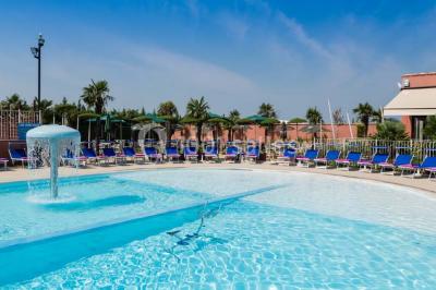Salle de restaurant lumineuse avec grandes baies vitrées, tables dressées et vue sur une terrasse extérieure.