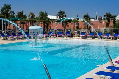 Salle de restaurant lumineuse avec grandes baies vitrées, tables dressées et vue sur une terrasse extérieure.