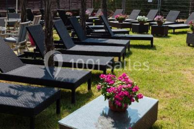 Salle de restaurant lumineuse avec grandes baies vitrées, tables dressées et vue sur une terrasse extérieure.