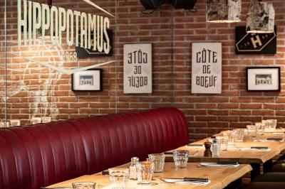 Miniature Location salle Boulogne-Billancourt (Hauts-de-Seine) - Hippopotamus Boulogne #4 Plat de viande rouge tranchée avec sauce au poivre, accompagné de frites, servi dans un plat ovale sur une table en bois.