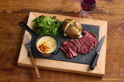 Miniature Location salle Boulogne-Billancourt (Hauts-de-Seine) - Hippopotamus Boulogne #15 Plat de viande rouge tranchée avec sauce au poivre, accompagné de frites, servi dans un plat ovale sur une table en bois.