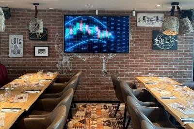 Plat de viande rouge tranchée avec sauce au poivre, accompagné de frites, servi sur un plateau avec un verre de vin rouge.