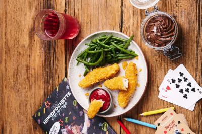 Plat de viande rouge tranchée avec sauce au poivre, accompagné de frites, servi sur un plateau avec un verre de vin rouge.