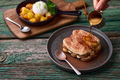 Plat de viande rouge tranchée avec sauce au poivre, accompagné de frites, servi sur un plateau avec un verre de vin rouge.