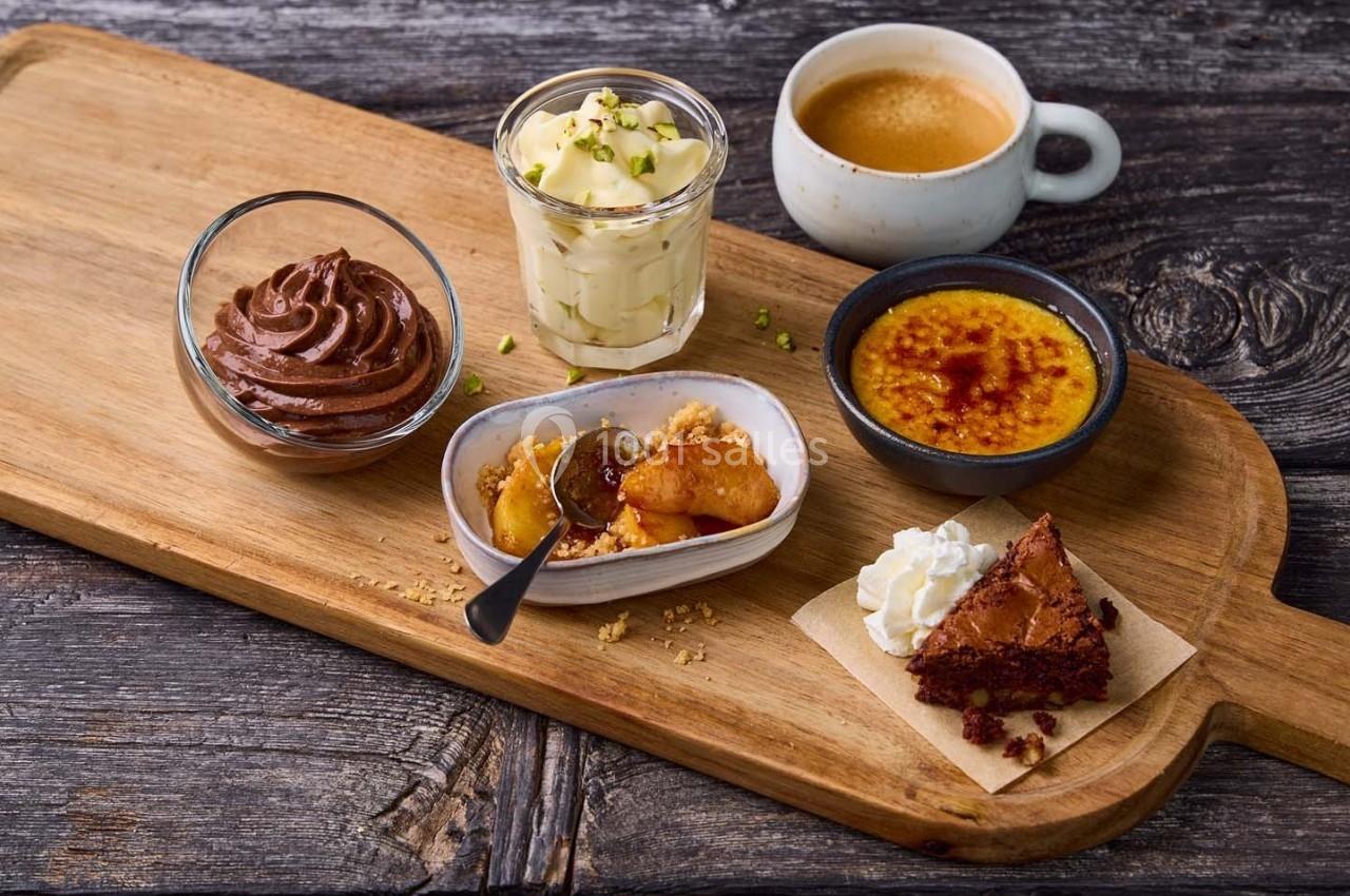 Plateau en bois avec mousse au chocolat, tiramisu, crème brûlée, crumble aux pommes, brownie et tasse de café.
