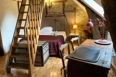 Miniature Chambre à thème Coq Chambre mansardée avec lit double, bureau en bois, malles anciennes et murs en pierre apparente.