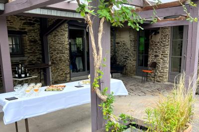 Miniature Cocktail sous préau extérieur Chambre mansardée avec lit double, bureau en bois, malles anciennes et murs en pierre apparente.