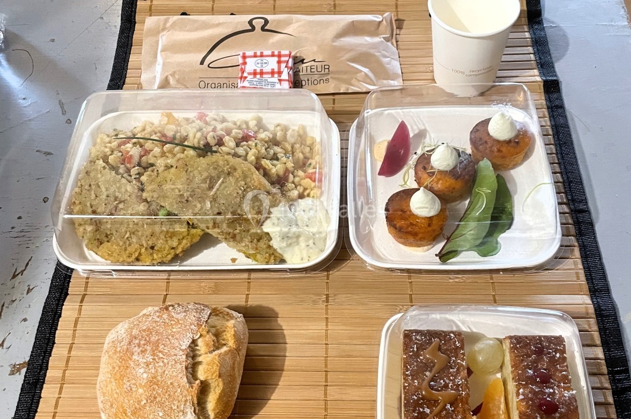 Repas composé de galettes, salade, pain, desserts variés et boisson, présenté sur un set en bambou.