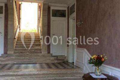 Escalier en pierre décoré de fleurs, menant à une pièce lumineuse avec carrelage en damier et vue sur un jardin.