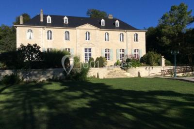 Escalier en pierre décoré de fleurs, menant à une pièce lumineuse avec carrelage en damier et vue sur un jardin.
