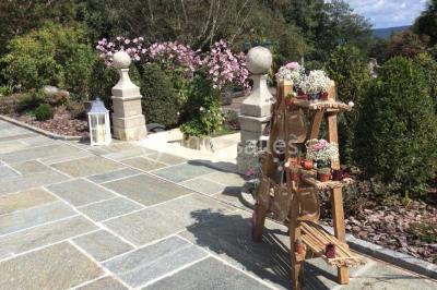 Escalier en pierre décoré de fleurs, menant à une pièce lumineuse avec carrelage en damier et vue sur un jardin.