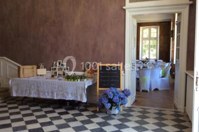 Escalier en pierre décoré de fleurs, menant à une pièce lumineuse avec carrelage en damier et vue sur un jardin.
