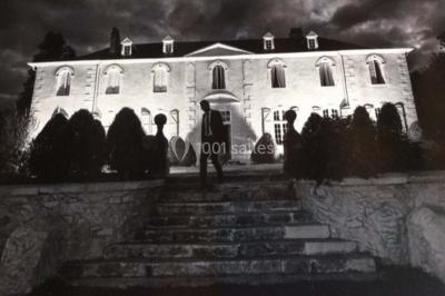 Escalier en pierre décoré de fleurs, menant à une pièce lumineuse avec carrelage en damier et vue sur un jardin.