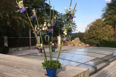 Escalier en pierre décoré de fleurs, menant à une pièce lumineuse avec carrelage en damier et vue sur un jardin.