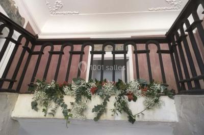 Escalier en pierre décoré de fleurs, menant à une pièce lumineuse avec carrelage en damier et vue sur un jardin.