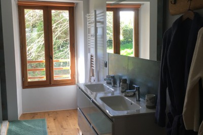 Piscine extérieure en bois devant une grande maison ancienne entourée d'un jardin arboré.
