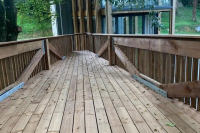 Piscine extérieure en bois devant une grande maison ancienne entourée d'un jardin arboré.