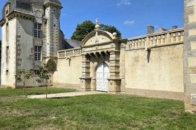 Façade éclairée d'un château à deux tours symétriques, vue de nuit avec des buissons au premier plan.