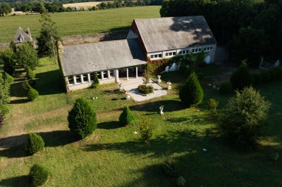 Façade éclairée d'un château à deux tours symétriques, vue de nuit avec des buissons au premier plan.