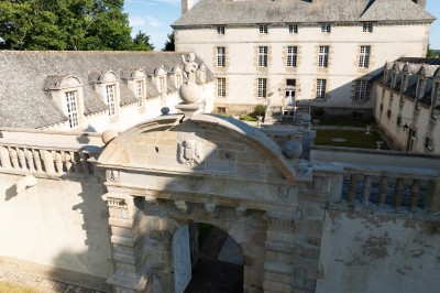 Façade éclairée d'un château à deux tours symétriques, vue de nuit avec des buissons au premier plan.