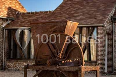 Chemin de campagne bordé de poteaux électriques et clôtures, traversant un paysage rural sous un ciel sombre.