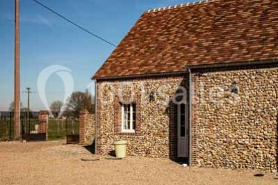 Chemin de campagne bordé de poteaux électriques et clôtures, traversant un paysage rural sous un ciel sombre.