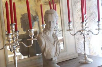 Miniature Location salle Tours (Indre-et-Loire) - La Grotte de la Roche aux Fées #10 Salle décorée dans une grotte avec des tables dressées, chandeliers rouges, plantes vertes et fleurs blanches et rouges.
