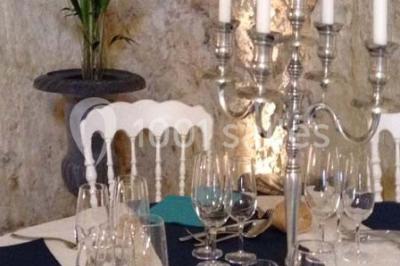 Miniature Location salle Tours (Indre-et-Loire) - La Grotte de la Roche aux Fées #17 Salle décorée dans une grotte avec des tables dressées, chandeliers rouges, plantes vertes et fleurs blanches et rouges.