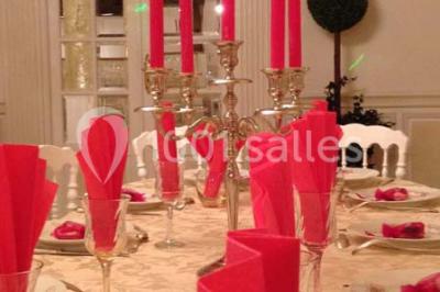 Miniature Location salle Tours (Indre-et-Loire) - La Grotte de la Roche aux Fées #18 Salle décorée dans une grotte avec des tables dressées, chandeliers rouges, plantes vertes et fleurs blanches et rouges.