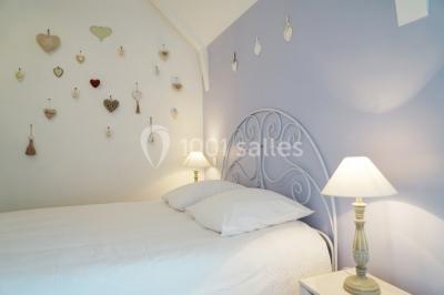 Table ronde décorée pour un événement, avec nappes beige, chaises blanches ornées de tissu orange et centre de table floral.