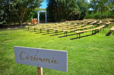 Table ronde décorée pour un événement, avec nappes beige, chaises blanches ornées de tissu orange et centre de table floral.