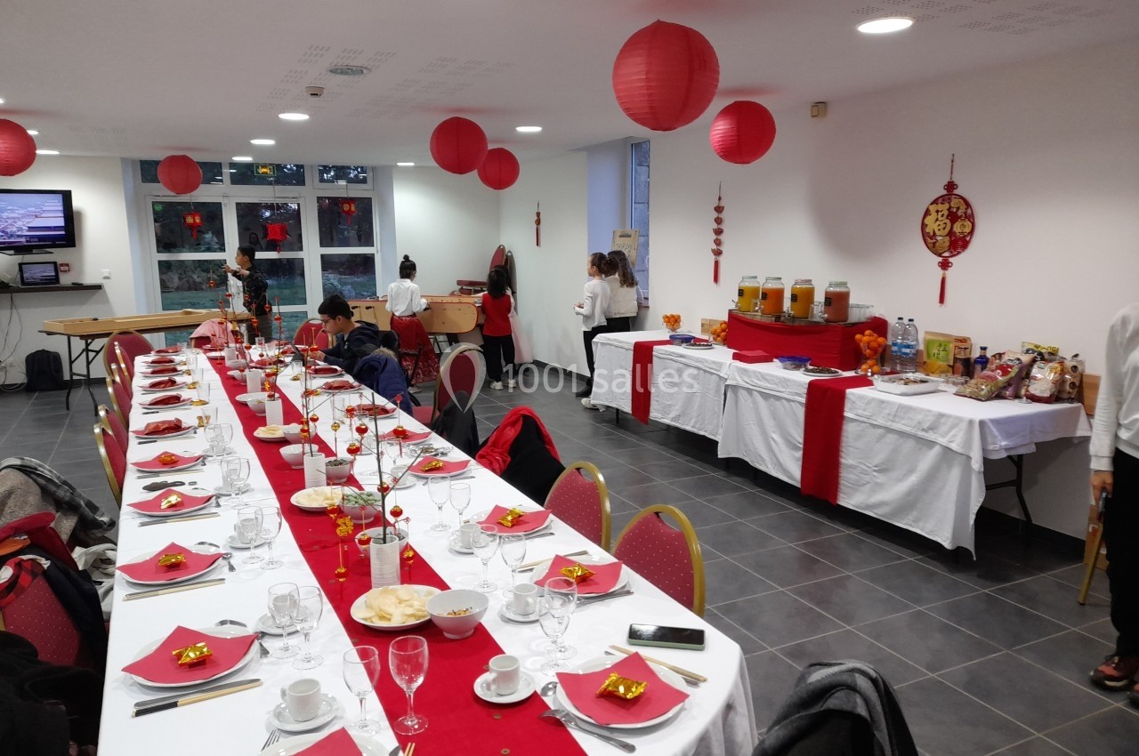 Salle décorée avec des lanternes rouges, table dressée pour un repas festif et buffet en arrière-plan.
