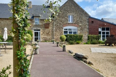 Table ronde décorée pour un événement, avec nappes beige, chaises blanches ornées de tissu orange et centre de table floral.